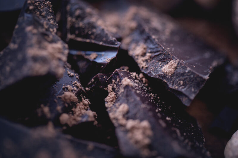 Dark chocolate bar crushed and sprinkled with cocoa powder with spices