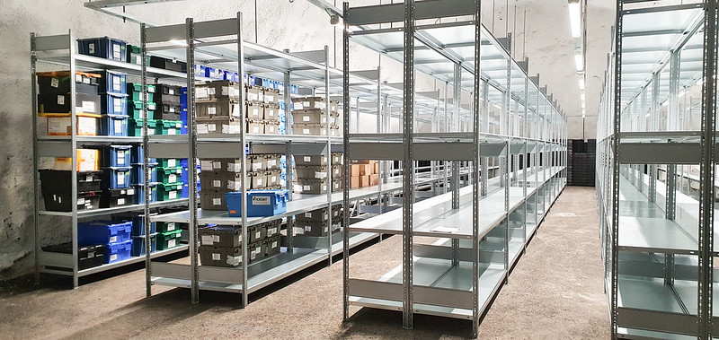 Indoor shelving units filled with plastic boxes containing seeds