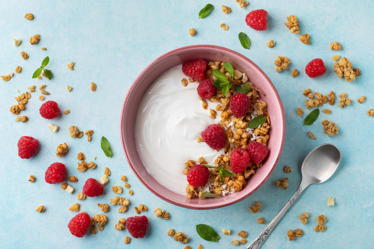 Bowl with greek yogurt, raspberries and granola.