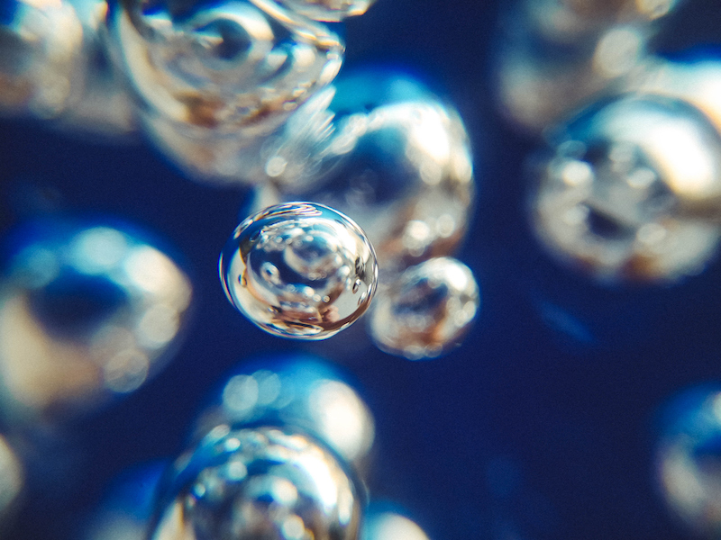 Extreme close up on an air bubble between other air bubbles and a blue background.