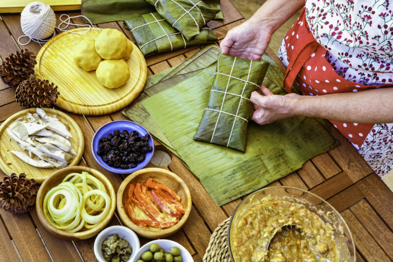 woman preparing hallacas with fresh ingredients on a wooden table
