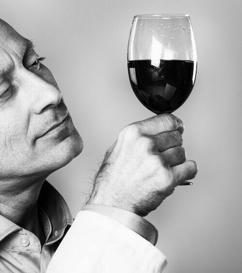 Man in lab coat holds wine glass up to light