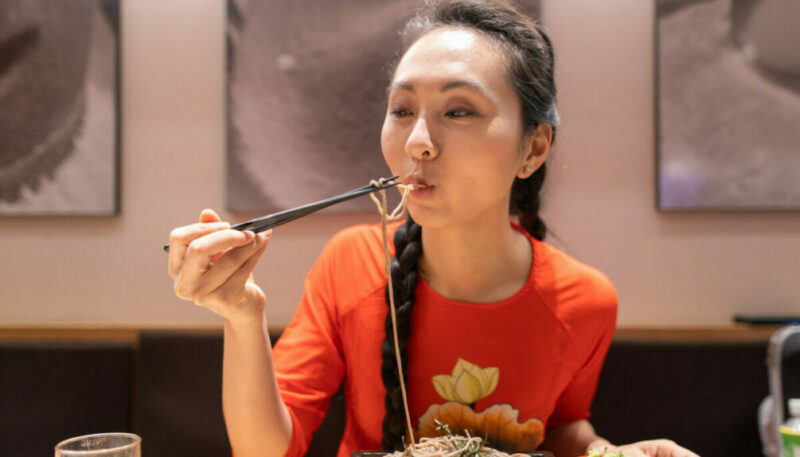 Young woman in Ado Dai eating Soba with chopsticks