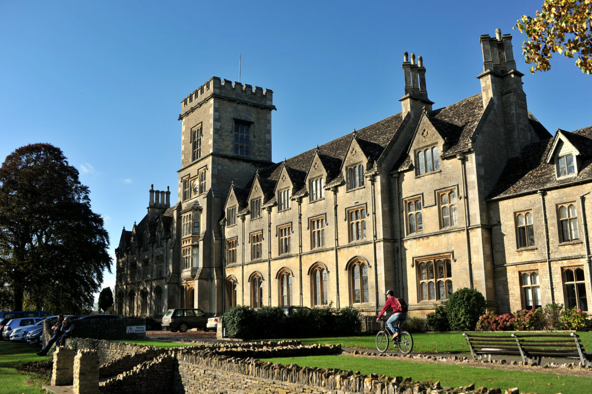 Royal Agricultural University in Gloucestershire on sunny day with student cycling