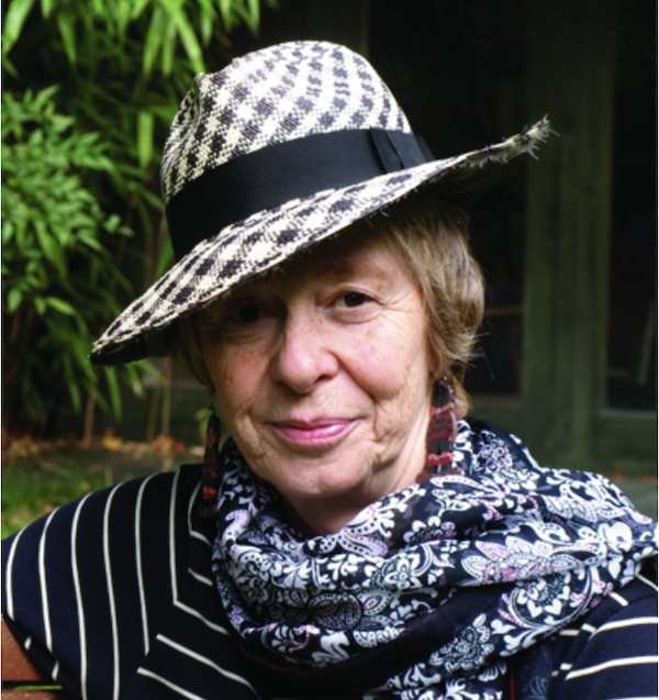 Michelle Berriedale-Johnson, in a scarf and chequered hat surrounded by trees