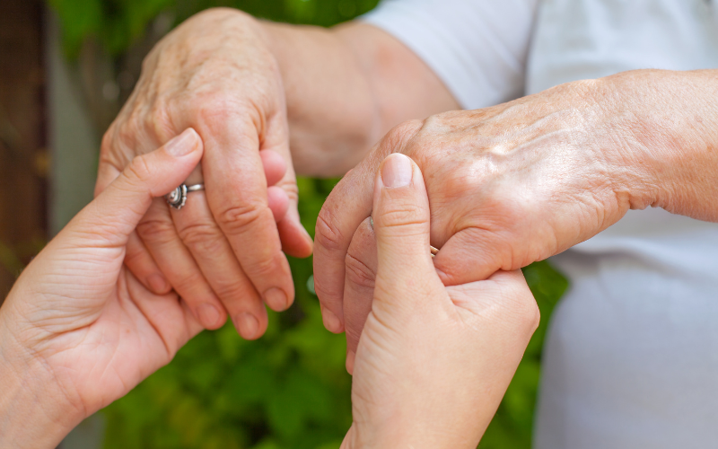 Young hands holding the aged hands of someone with Parkinson's