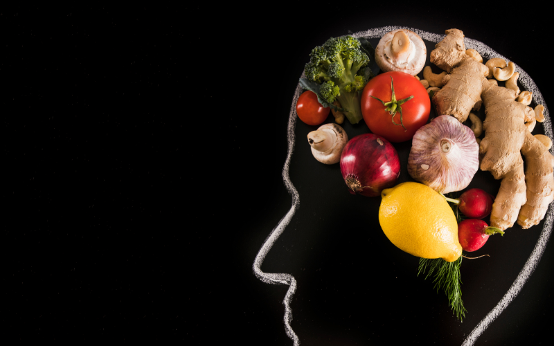 A chalk outline of a human head against a black background with food depicting a human brain
