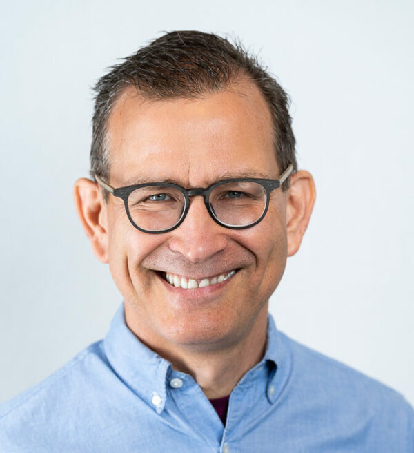 man wearing glasses and a blue shirt smiling