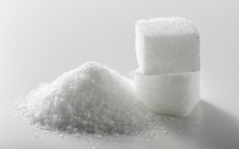 A close-up of sugar cubes next to a pile of sugar granules