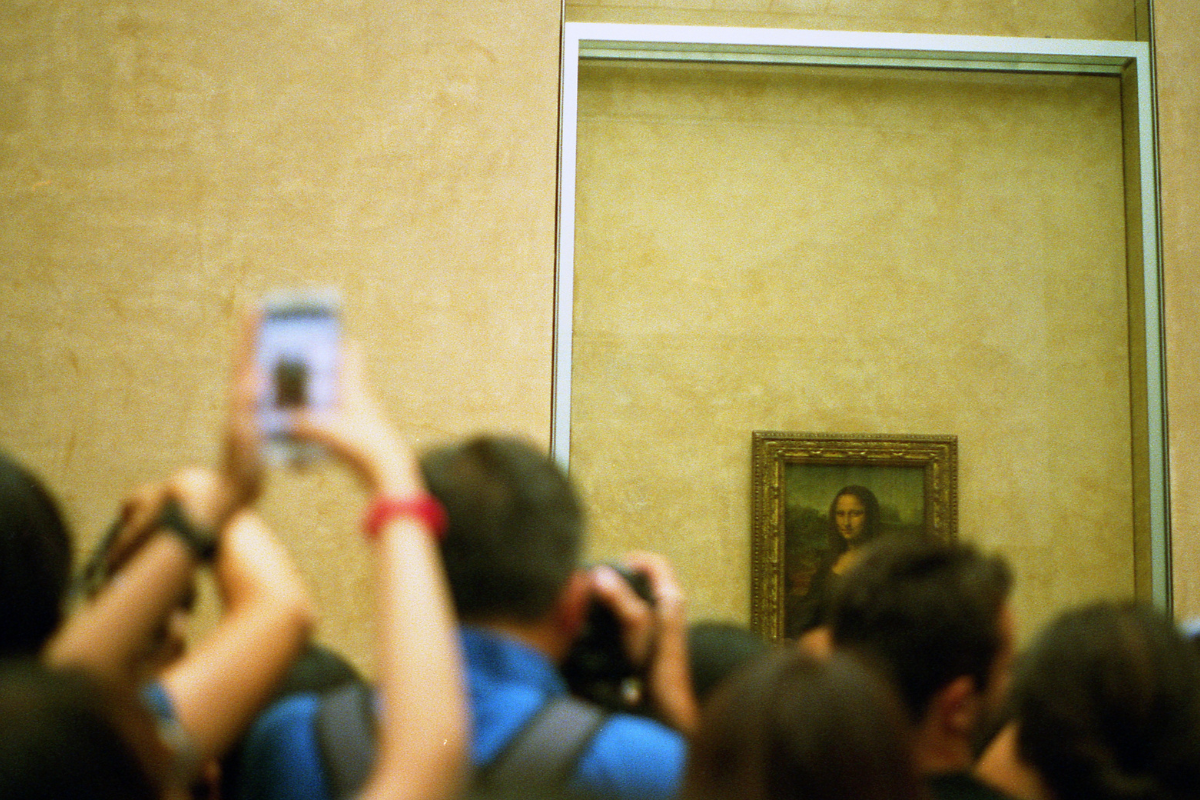 A crowd of tourists photographing the Mona Lisa painting