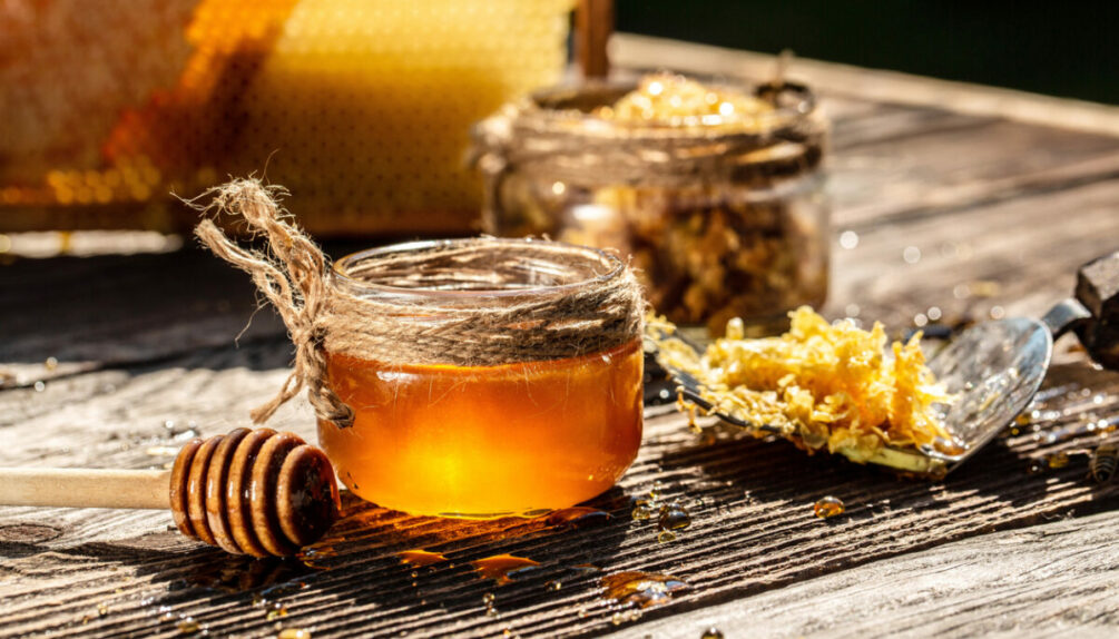 Honey bee and Honeycomb with honey dipper on wooden table