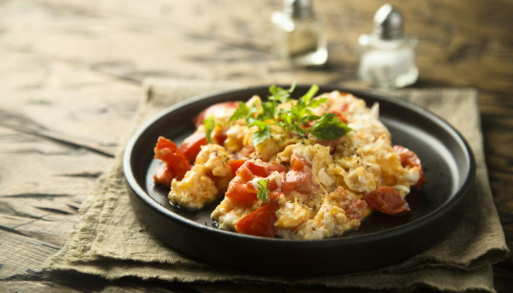 scrambled eggs and tomatoes on plate with garnish