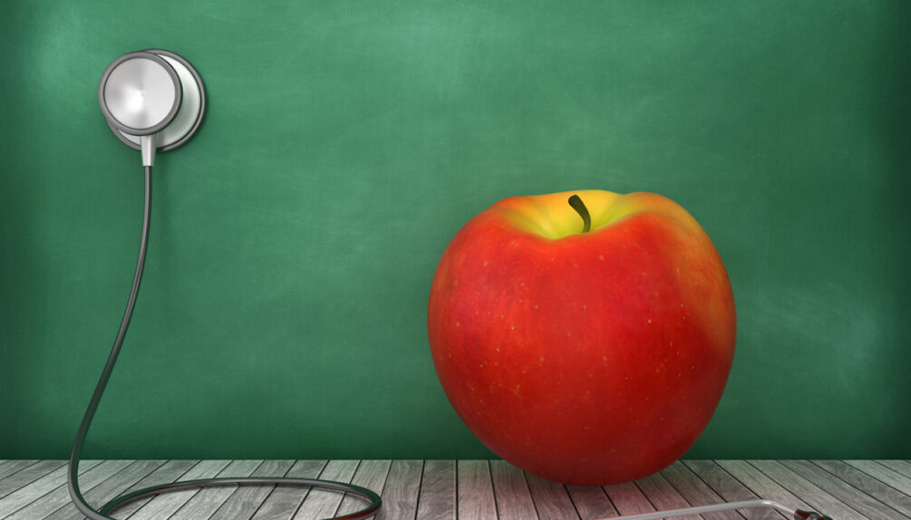 stethescope with red apple on green wall
