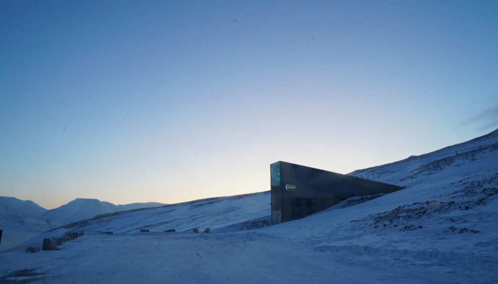 snowy and icy landscape with mountains, featuring the Svalbard Global Seed Vault in the centre