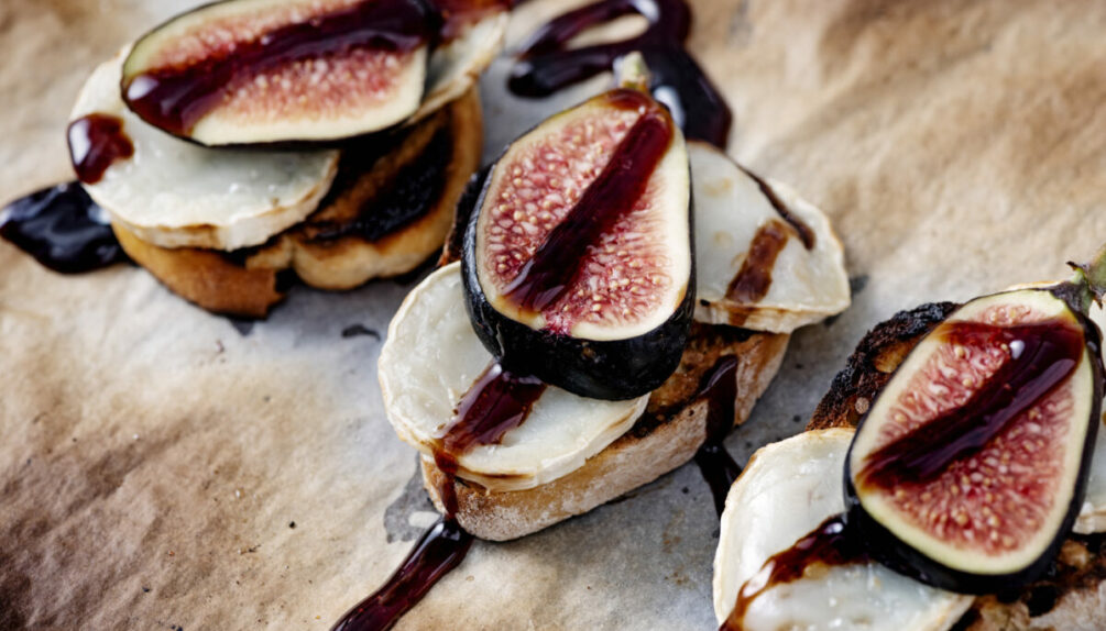 bread slices topped with cheese and figs, drizzled with balsamic vinegar and places on a wooden board