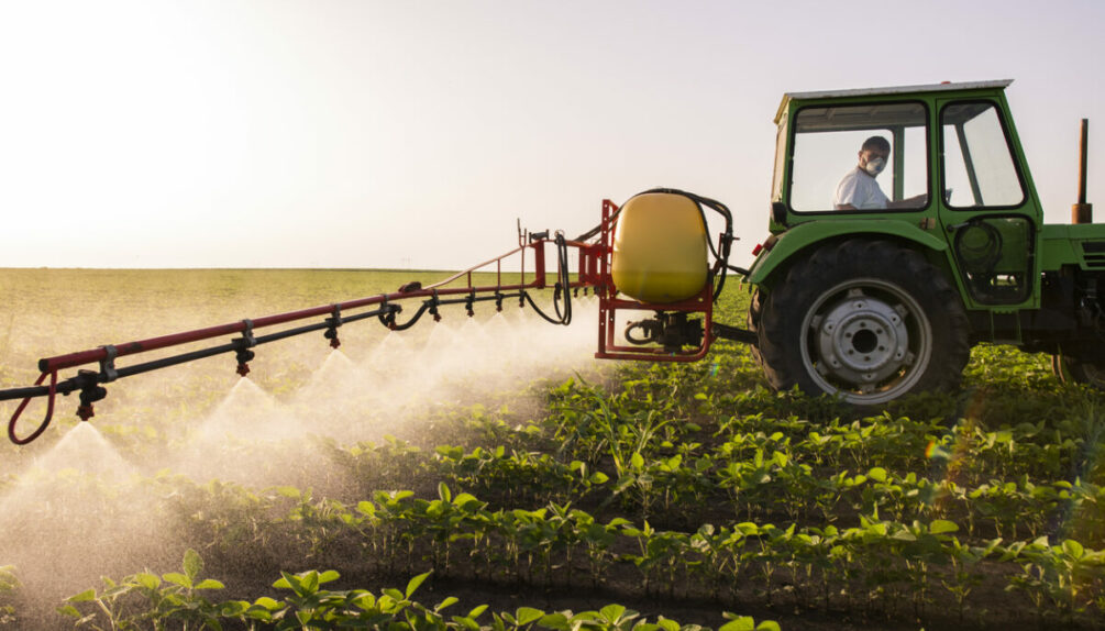 farmer spraying crops with fertiliser mist on a bright morning