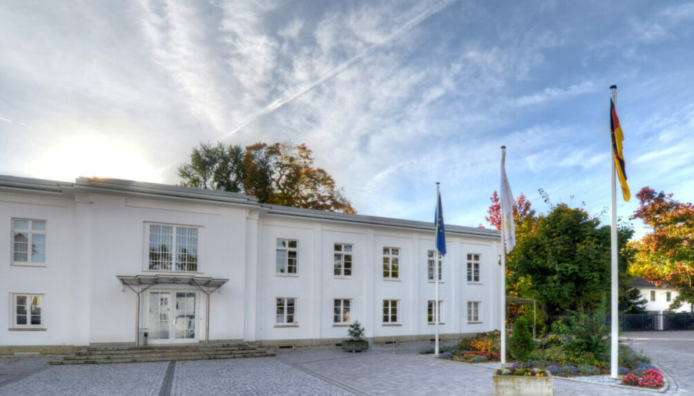 Exterior of the Bundeskartellamt building on a sunny blue sky day with german flag on the foreground