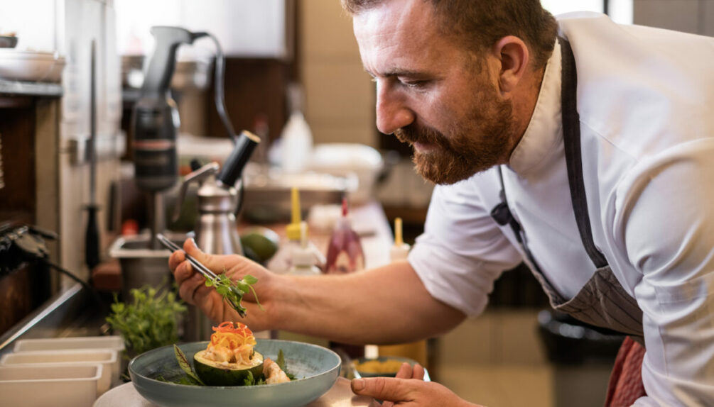 chef in white puts finishing touches to a dish