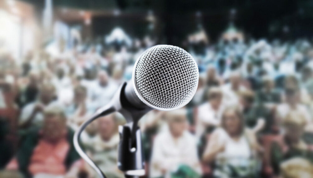 microphone on stage in front of a large crowd in a theatre