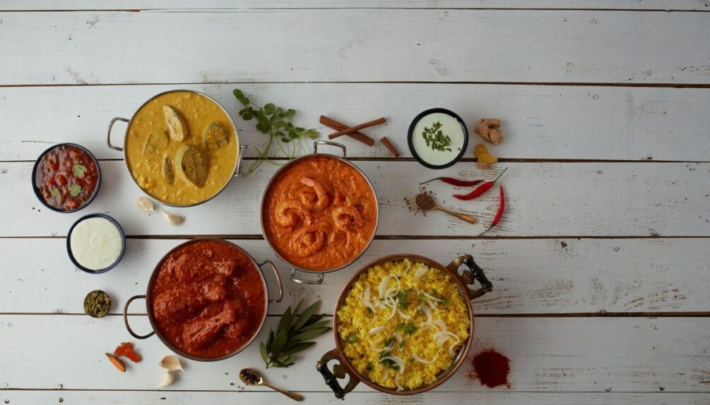 Colourful curry dishes on white wooden background