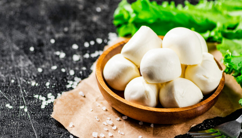 Mozzarella cheese in a wooden plate with lettuce