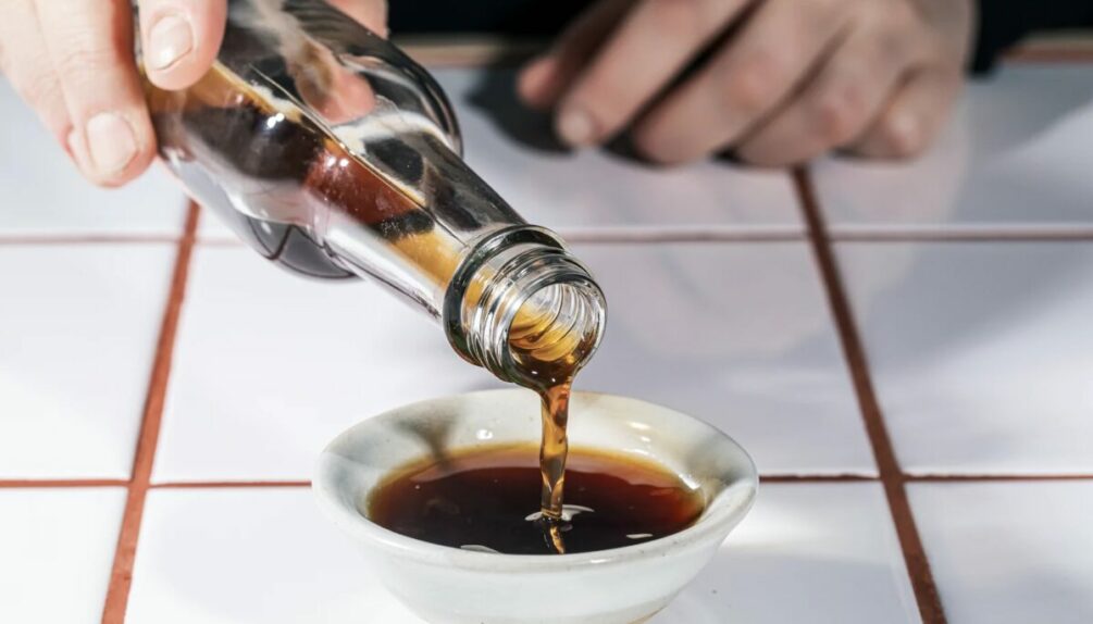 soy sauce poured into small white dish on white tile countertop
