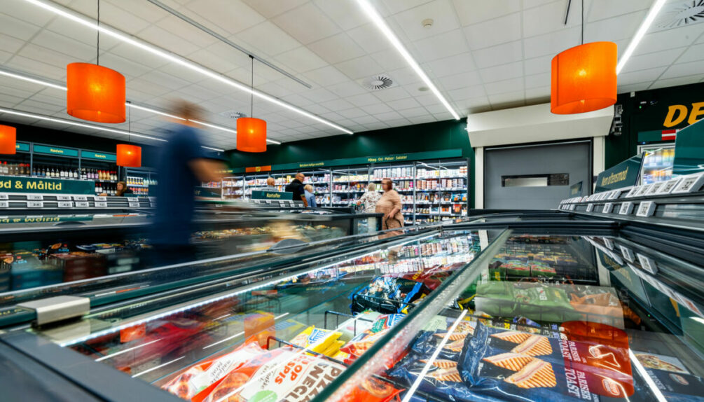 supermarket fridge cases and displays with orange light shades hanging from ceiling