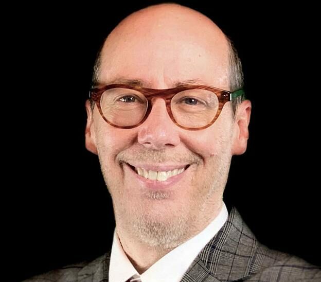 Man wearing glasses and a time smiling