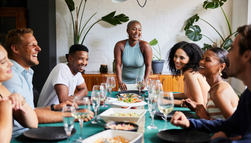 Young woman laughing while hosting a dinner party for a group of friends