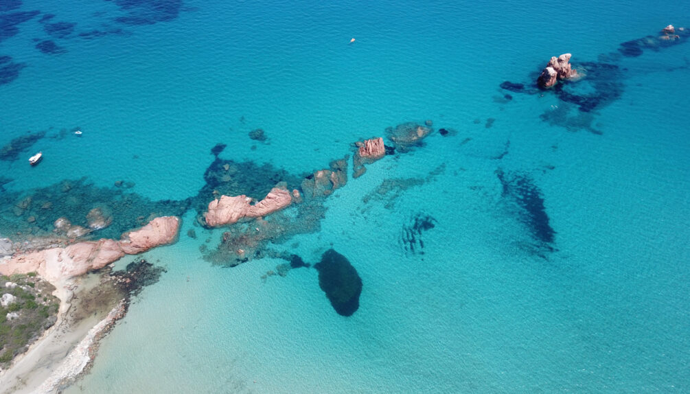 Aerial view of red rocks against blue Mediterranean Sea in Tortolì, Sardinia, Italy