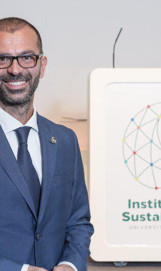 Prof. Lorenzo Fioramonti. smiling in front og a sign for the Institute for Sustainability University of Surrey