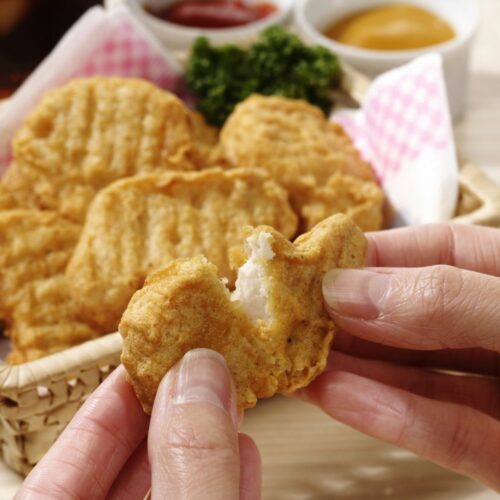 A chicken nugget being pulled apart to show the meat inside