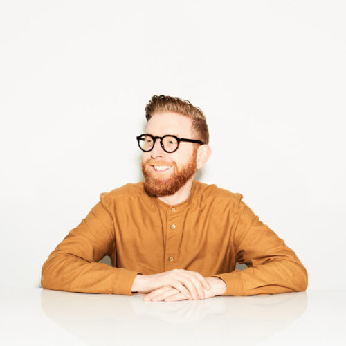 Paul Young chocolatier in orange top with white background smiling